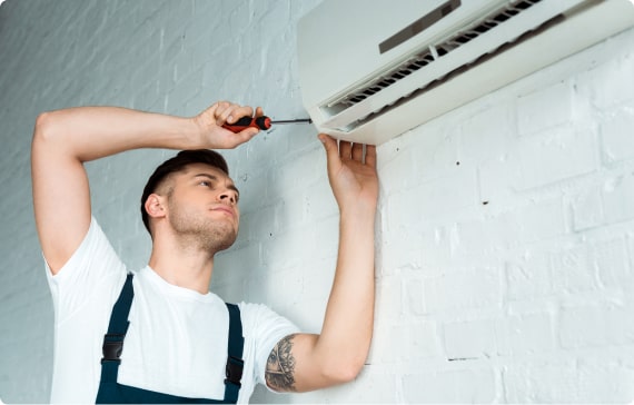 Technician repairing wall-mounted air conditioning unit, emphasizing HVAC maintenance and service in residential settings.