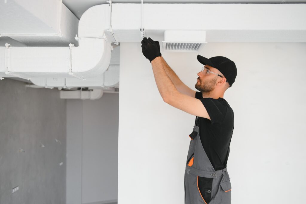 Ventilation cleaning specialist repairing HVAC ductwork in a modern indoor setting, emphasizing professional duct installation and maintenance services.