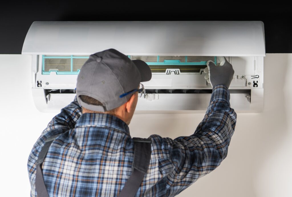 Technician performing maintenance on a ductless mini-split air conditioning unit, showcasing HVAC repair services for energy-efficient climate control in residential settings.