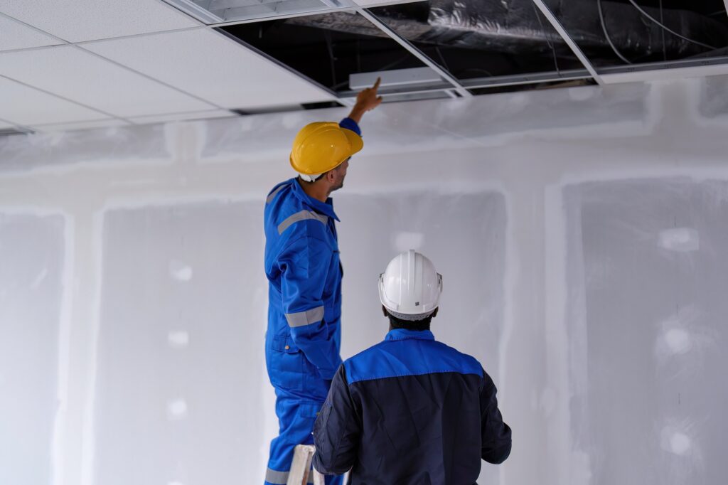Construction workers inspecting ductwork in a new building, highlighting professional HVAC installation and maintenance.