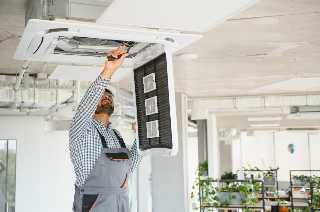 Professional technician maintaining modern air conditioning unit indoors, showcasing HVAC repair services relevant to San Diego's climate.